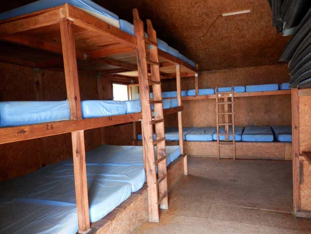 Wooden bunk beds with blue mattresses inside a rustic refuge room at Refuge de l'Onda.