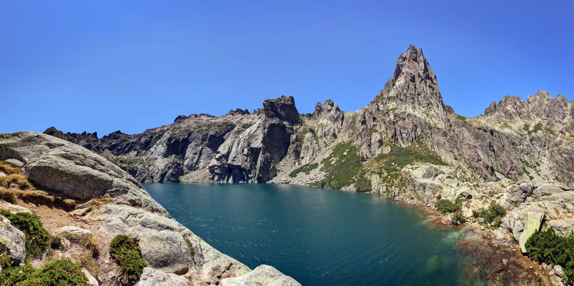 Lac de Capitello in Haute Corse with rugged mountains and deep blue alpine lake.