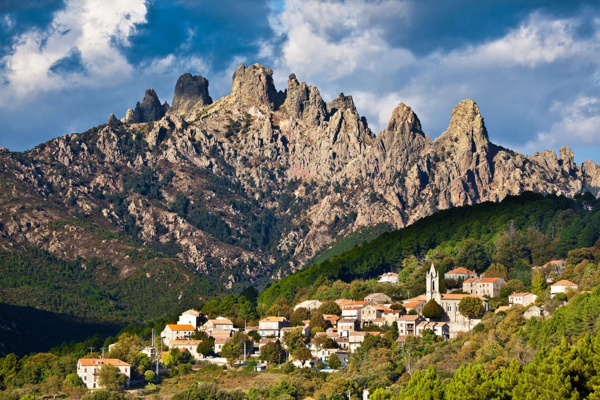 Mountain village of Zonza, Corsica, nestled below jagged Aiguilles de Bavella peaks.